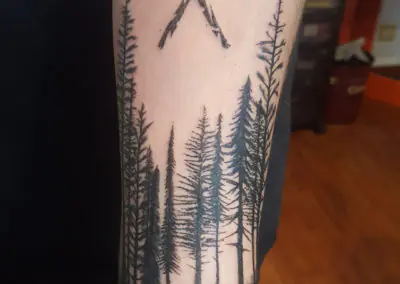 Tatouage de forêt de sapins en blackwork sur l'avant-bras