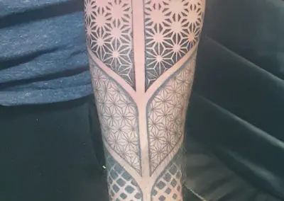 Tatouage géométrique aux motifs asanoha en dotwork sur la jambe