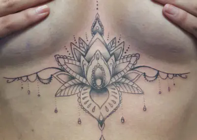 Tatouage lotus ornemental et pendeloques sur le sternum