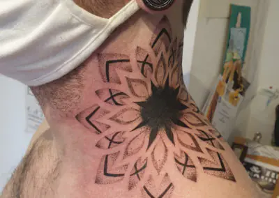 Tatouage mandala en dotwork avec motifs géométriques sur la nuque