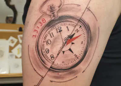 Tatouage réaliste de montre à gousset et boussole sur le bras