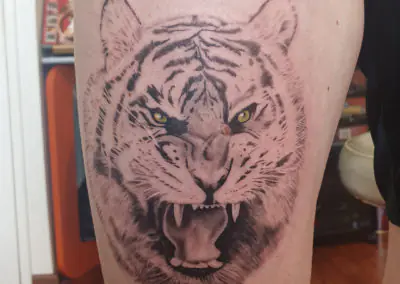 Tatouage de tigre réaliste en noir et gris sur la cuisse