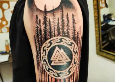 Tatouage valknut et forêt nordique en blackwork sur l'épaule